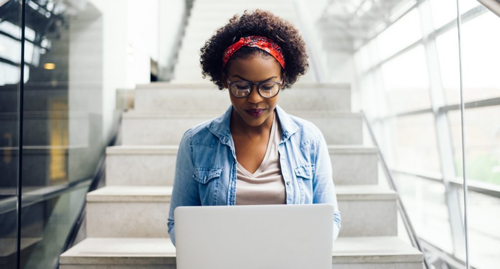 focused student sitting on stairs using a laptop